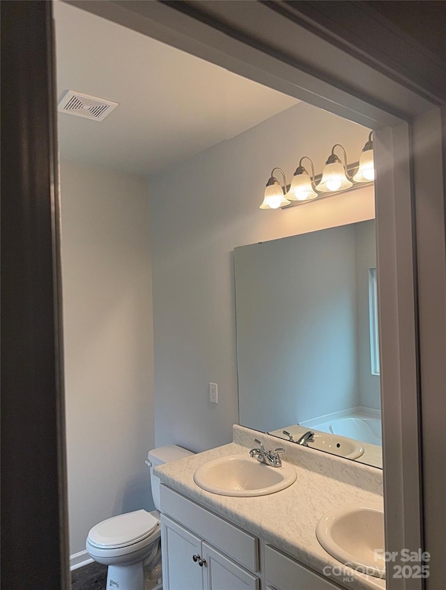 full bathroom featuring double vanity and toilet