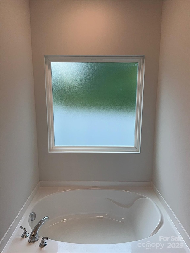 bathroom featuring plenty of natural light and a bath