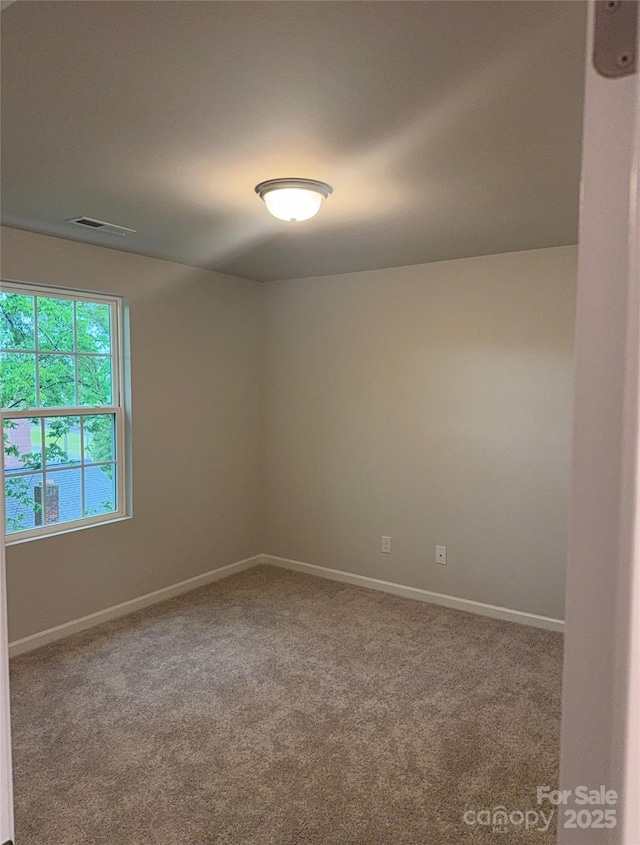 carpeted spare room featuring baseboards