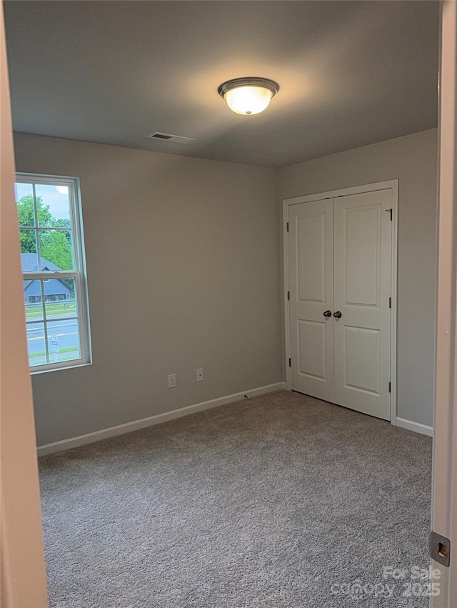 carpeted spare room featuring baseboards