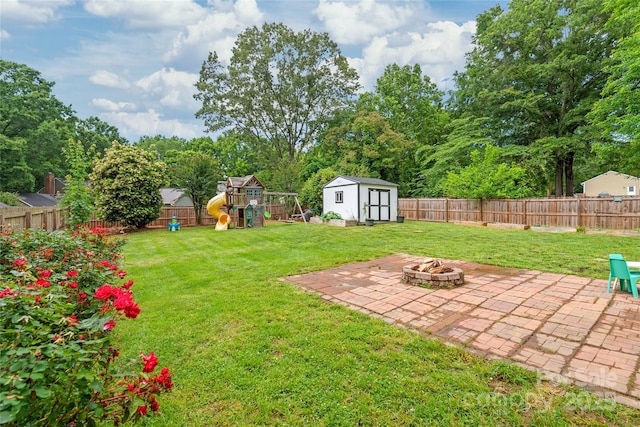 view of yard with a patio area, an outdoor fire pit, a playground, a shed, and an outbuilding
