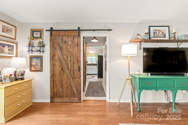 living area with light wood-style flooring, baseboards, and a barn door