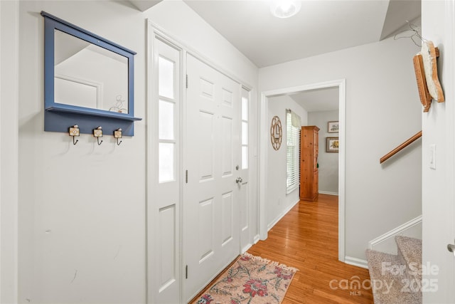 entrance foyer with light wood-style floors, baseboards, and stairs