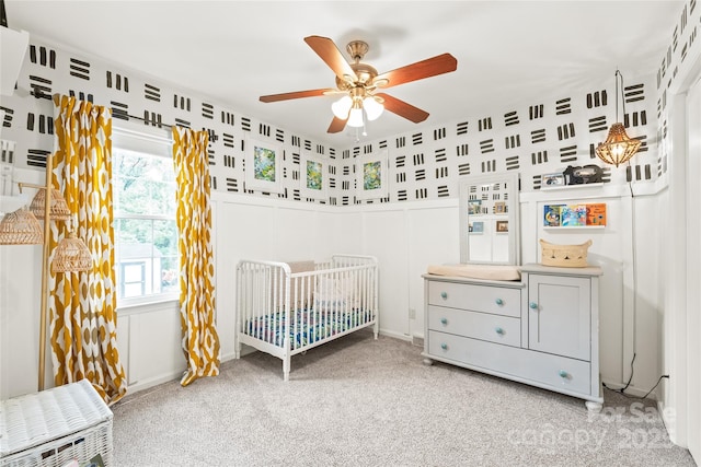 bedroom featuring carpet, a nursery area, and a ceiling fan