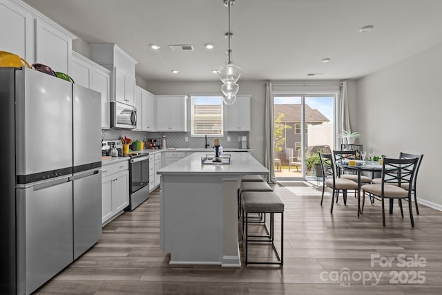 5625 Axil Ln, Charlotte, NC 28269 - kitchen with appliances with stainless steel finishes, wood finished floors, recessed lighting, light countertops, and white cabinetry