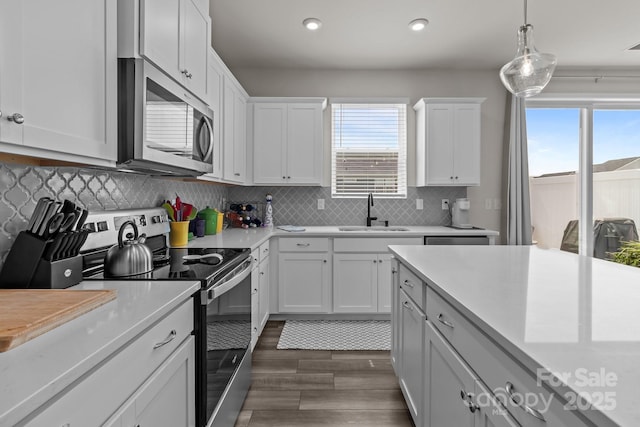 5625 Axil Ln, Charlotte, NC 28269 - kitchen with stainless steel appliances, a sink, dark wood-type flooring, light countertops, and tasteful backsplash