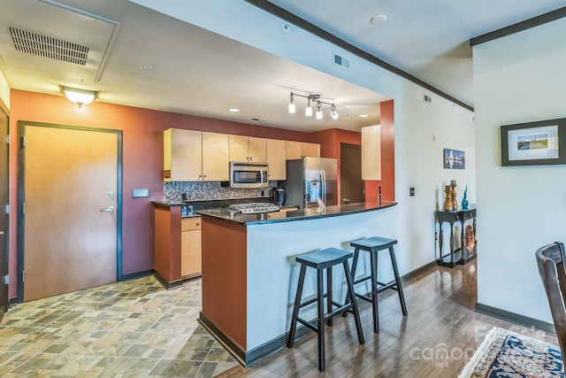 715 N Church St Unit 613, Charlotte, NC 28202 - kitchen featuring appliances with stainless steel finishes, backsplash, dark countertops, a peninsula, and a breakfast bar