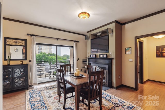 715 N Church St Unit 613, Charlotte, NC 28202 - dining area with ornamental molding, light wood-type flooring, a fireplace, and baseboards