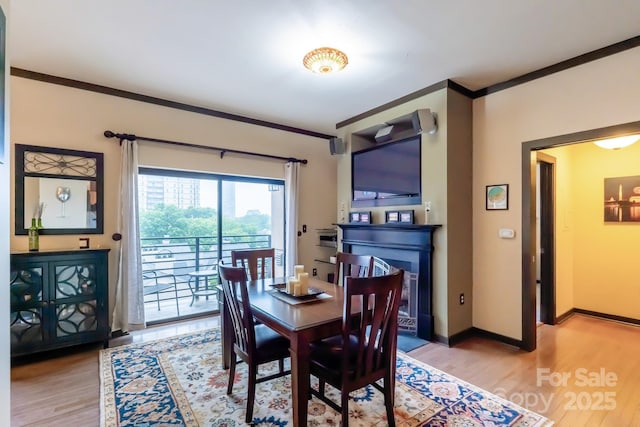 715 N Church St Unit 613, Charlotte, NC 28202 - dining space featuring light wood-style flooring, crown molding, a fireplace, and baseboards