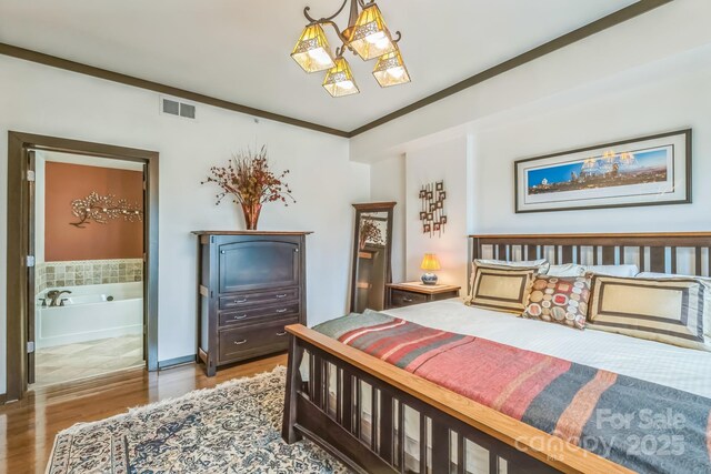 715 N Church St Unit 613, Charlotte, NC 28202 - bedroom featuring wood finished floors, ensuite bath, a chandelier, and ornamental molding