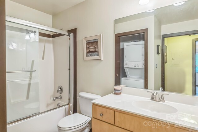 715 N Church St Unit 613, Charlotte, NC 28202 - bathroom featuring stacked washer / drying machine, toilet, vanity, and bath / shower combo with glass door