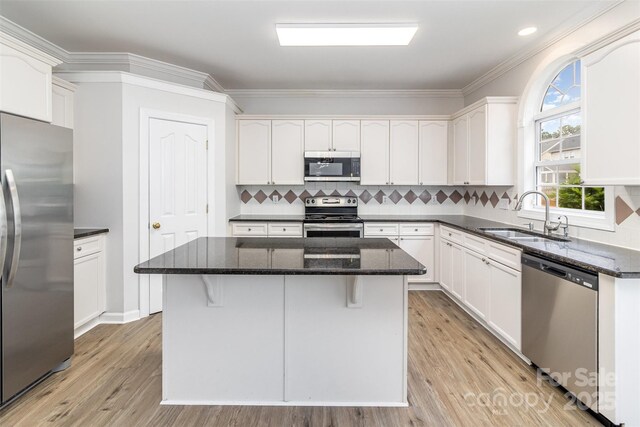 11526 Mcginns Trace Ct, Charlotte, NC 28277 - kitchen with stainless steel appliances, a sink, dark stone countertops, light wood-style floors, and ornamental molding