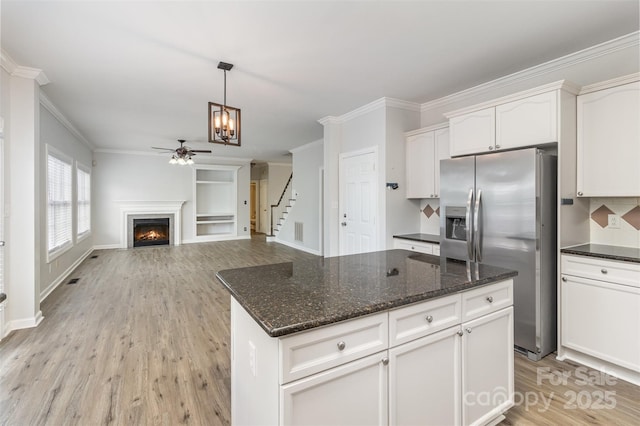 11526 Mcginns Trace Ct, Charlotte, NC 28277 - kitchen with stainless steel fridge, a ceiling fan, light wood finished floors, a warm lit fireplace, and white cabinetry