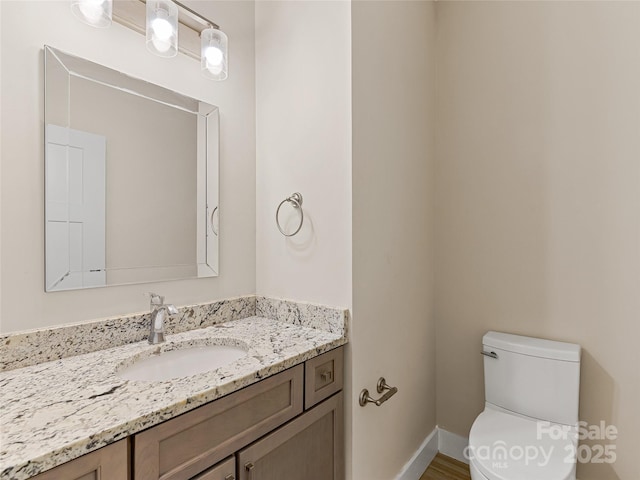 bathroom featuring toilet, vanity, and baseboards