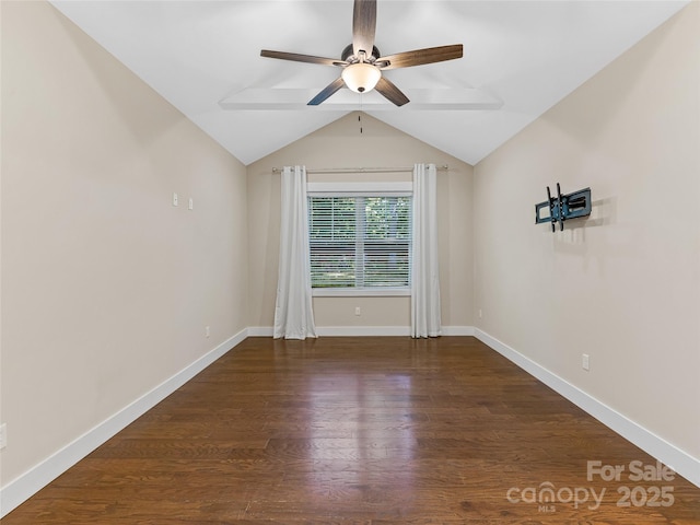 empty room with a ceiling fan, vaulted ceiling, wood finished floors, and baseboards