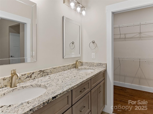 full bathroom featuring double vanity, wood finished floors, and a spacious closet