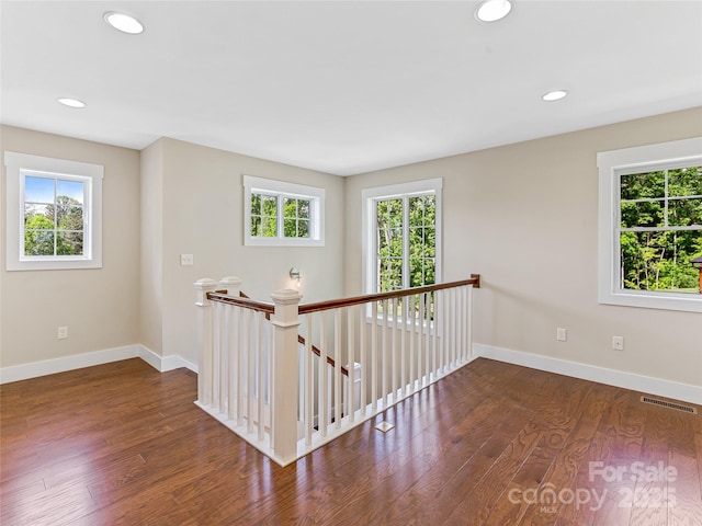 hall featuring an upstairs landing, baseboards, wood finished floors, and recessed lighting