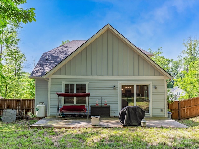 rear view of house featuring a shingled roof, board and batten siding, and a patio area