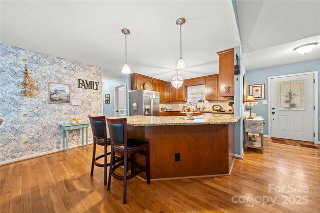 5764 Grassy Creek Rd, Denver, NC 28037 - kitchen featuring stainless steel fridge with ice dispenser, wallpapered walls, light wood-style flooring, baseboards, and light stone countertops