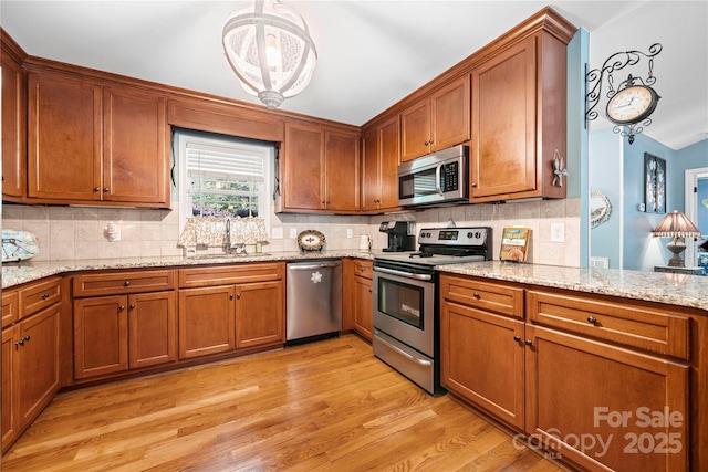 5764 Grassy Creek Rd, Denver, NC 28037 - kitchen featuring appliances with stainless steel finishes, a sink, light wood-type flooring, and brown cabinetry