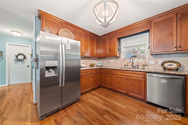 5764 Grassy Creek Rd, Denver, NC 28037 - kitchen featuring appliances with stainless steel finishes, a sink, brown cabinetry, and light wood finished floors