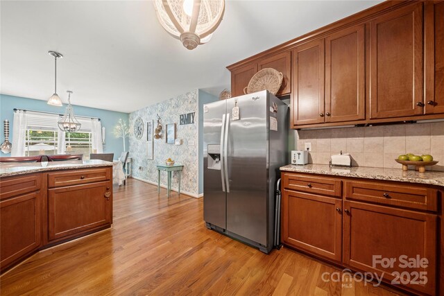5764 Grassy Creek Rd, Denver, NC 28037 - kitchen featuring stainless steel refrigerator with ice dispenser, light wood-type flooring, brown cabinetry, wallpapered walls, and hanging light fixtures