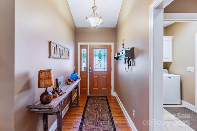 foyer with washer / clothes dryer, light wood-style floors, and baseboards