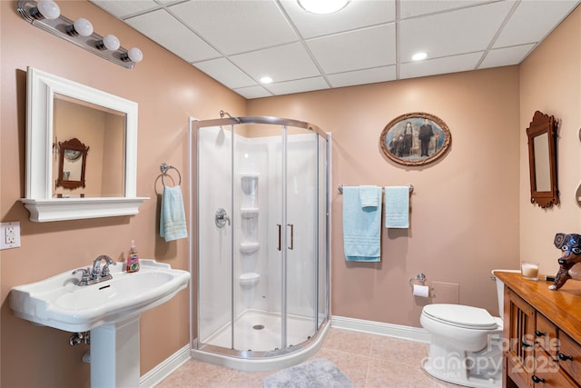 full bath featuring a drop ceiling, baseboards, a shower stall, toilet, and tile patterned floors