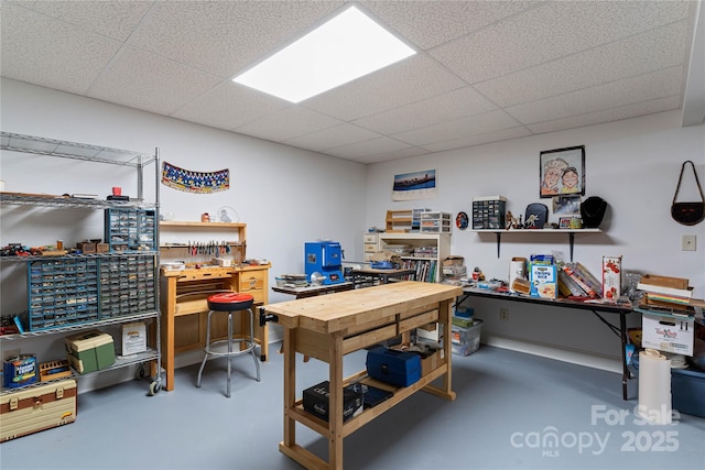 office space with a workshop area, a paneled ceiling, and finished concrete floors