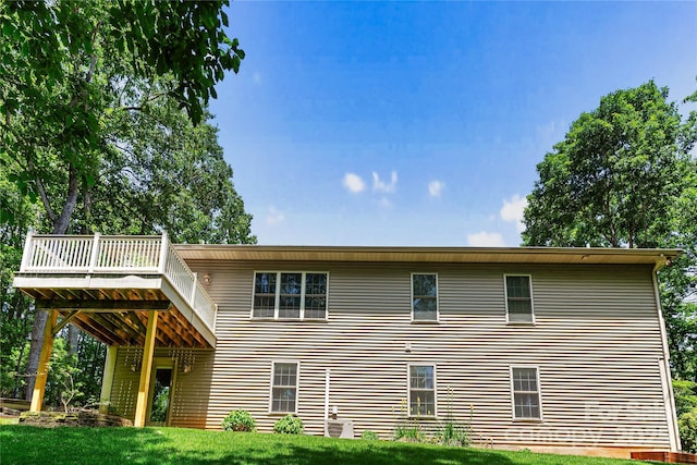 rear view of house featuring a wooden deck and a lawn