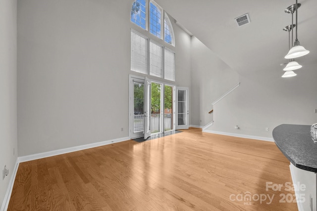 120F Steinbeck Way, Mooresville, NC 28117 - unfurnished living room featuring stairs, baseboards, light wood-type flooring, and a high ceiling