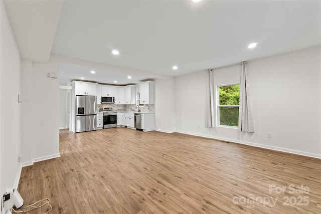 60 Valley St NW, Concord, NC 28025 - unfurnished living room featuring light wood-type flooring, recessed lighting, baseboards, and a sink