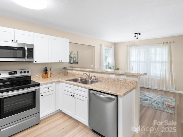 87 Markley Dr, Flat Rock, NC 28731 - kitchen with stainless steel appliances, a sink, a peninsula, light wood-type flooring, and white cabinets