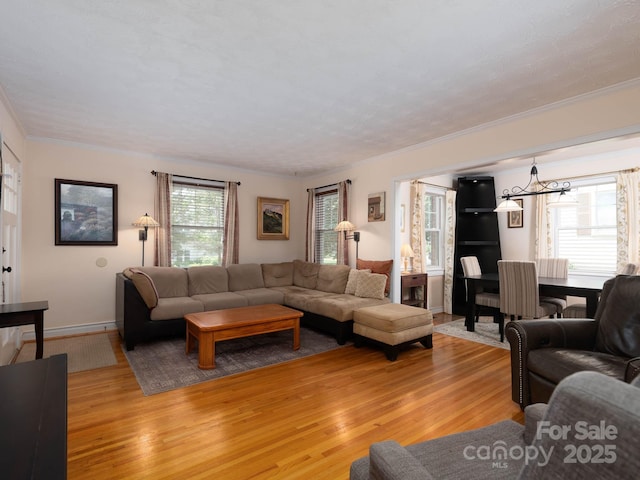 living room featuring light wood-style flooring, ornamental molding, and a chandelier