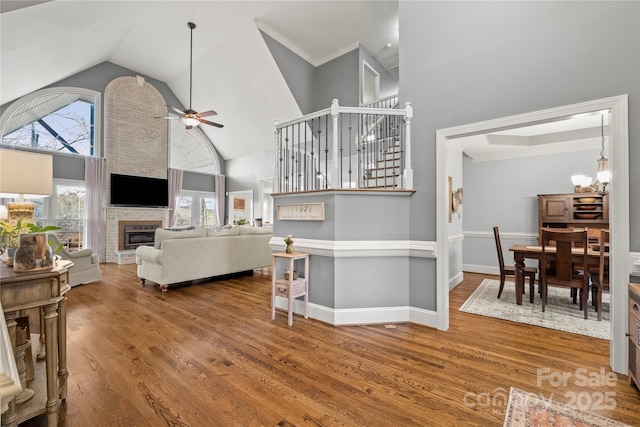 3115 Duck Point Dr, Monroe, NC 28110 - living room with high vaulted ceiling, ceiling fan, wood finished floors, a brick fireplace, and stairway