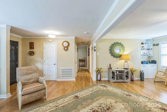 sitting room with crown molding, wood finished floors, and baseboards
