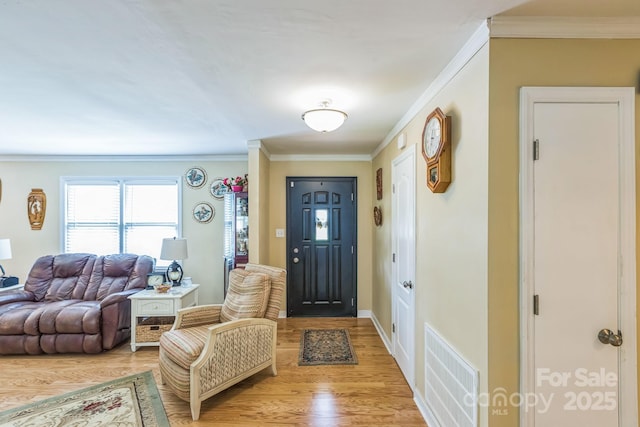 foyer entrance with light wood-style flooring, crown molding, and baseboards