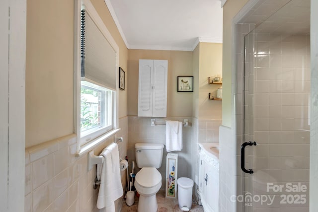 full bathroom with tile walls, toilet, a shower stall, crown molding, and wainscoting