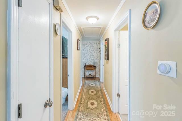 hallway featuring attic access, light wood-style floors, and baseboards