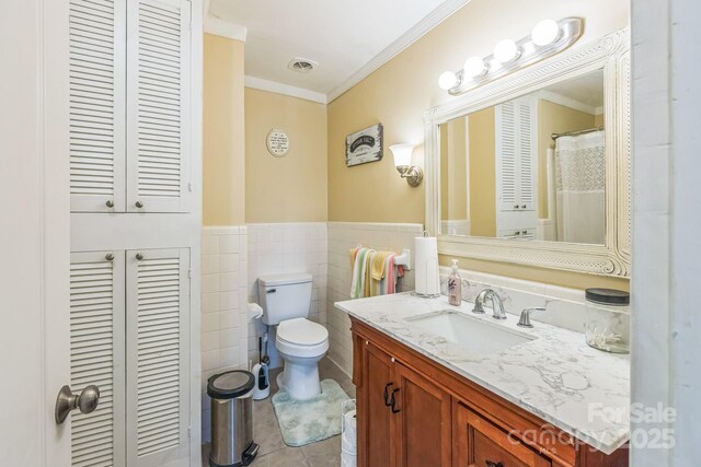 full bathroom with tile patterned flooring, ornamental molding, toilet, vanity, and a closet