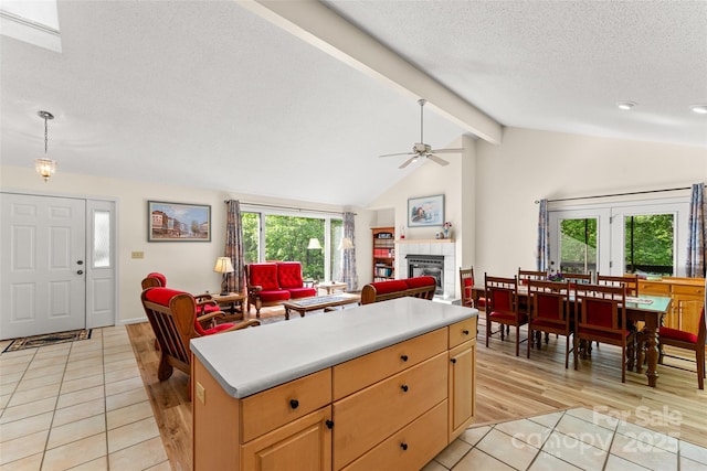 kitchen with light tile patterned flooring, ceiling fan, healthy amount of natural light, a tiled fireplace, and a textured ceiling
