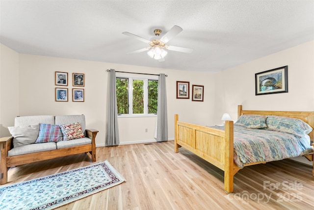 bedroom featuring wood finished floors, ceiling fan, baseboards, and a textured ceiling