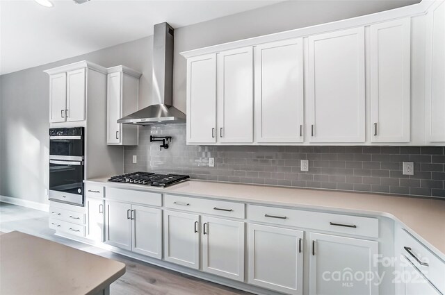 7517 Lancaster Hwy Unit 5, Waxhaw, NC 28173 - kitchen featuring wall chimney range hood, stainless steel appliances, white cabinets, light countertops, and light wood finished floors