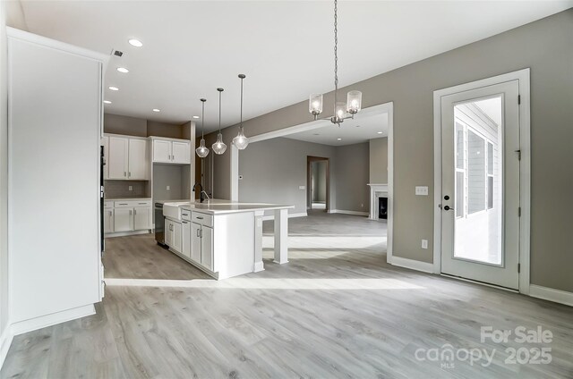 7517 Lancaster Hwy Unit 5, Waxhaw, NC 28173 - kitchen featuring open floor plan, white cabinets, light wood finished floors, pendant lighting, and a center island with sink
