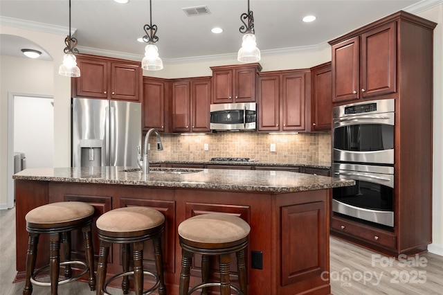 10502 Old Ardrey Kell Rd, Charlotte, NC 28277 - kitchen featuring appliances with stainless steel finishes, a sink, decorative backsplash, light wood finished floors, and dark stone counters