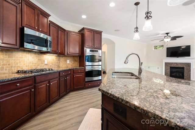 10502 Old Ardrey Kell Rd, Charlotte, NC 28277 - kitchen featuring appliances with stainless steel finishes, a sink, ceiling fan, arched walkways, and decorative backsplash