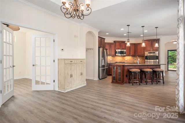 10502 Old Ardrey Kell Rd, Charlotte, NC 28277 - kitchen with stainless steel appliances, arched walkways, a breakfast bar area, backsplash, and recessed lighting