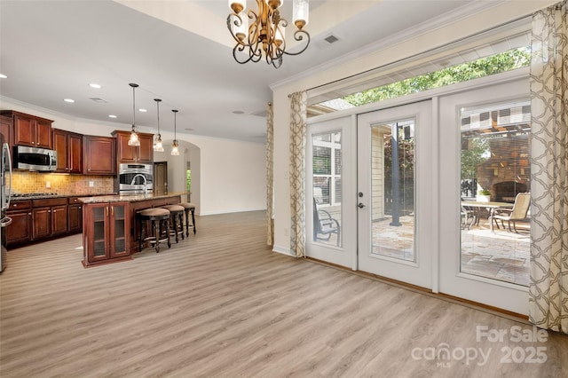 10502 Old Ardrey Kell Rd, Charlotte, NC 28277 - kitchen with stainless steel appliances, ornamental molding, a kitchen breakfast bar, arched walkways, and decorative backsplash