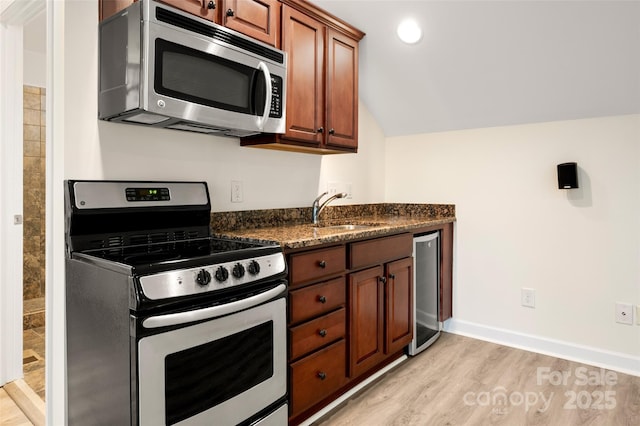10502 Old Ardrey Kell Rd, Charlotte, NC 28277 - kitchen with appliances with stainless steel finishes, a sink, light wood finished floors, brown cabinetry, and dark stone counters