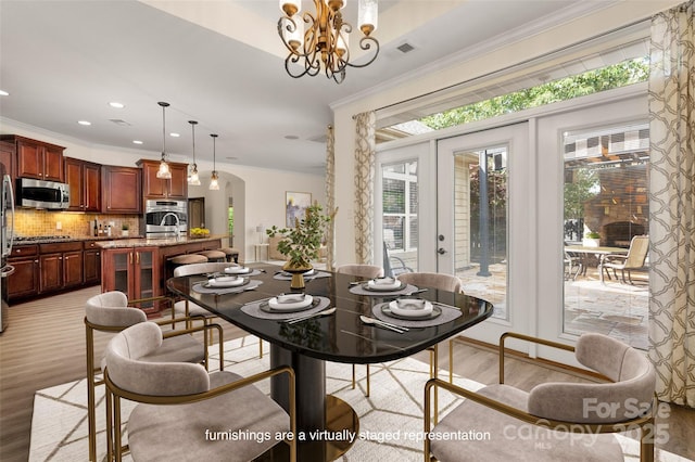 10502 Old Ardrey Kell Rd, Charlotte, NC 28277 - dining area with light wood finished floors, crown molding, arched walkways, a chandelier, and recessed lighting
